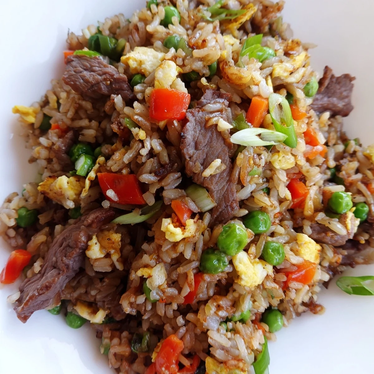 Steaming bowl of homemade Beef Fried Rice with Mixed Vegetables and Egg, garnished with sliced green onions and served with chopsticks.