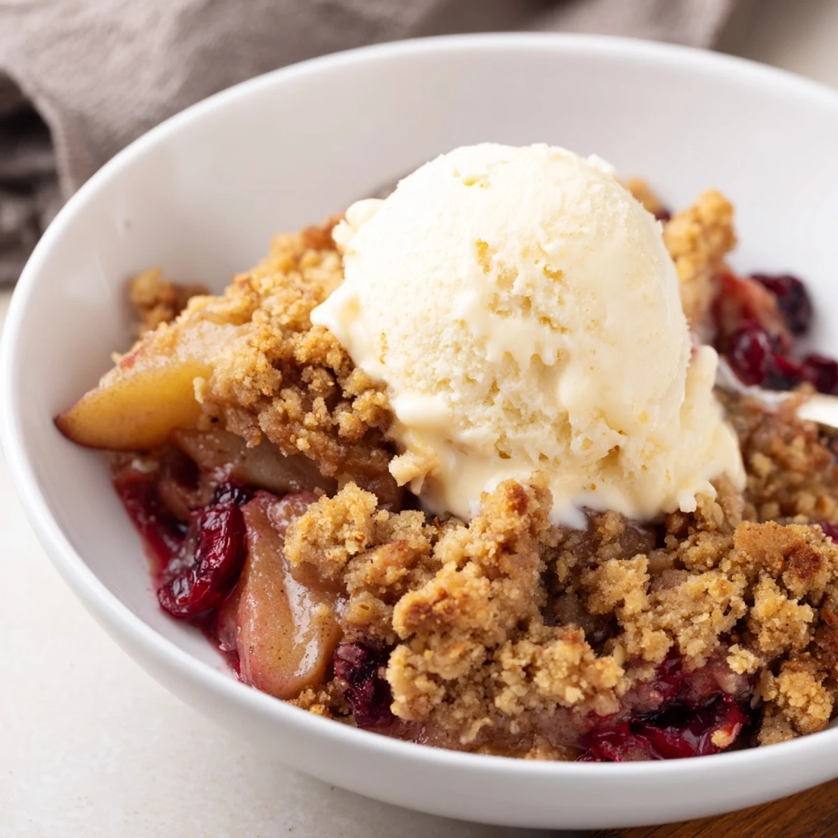 Freshly baked Spiced Pear and Cranberry Crumble bubbling in a dish, with a golden oat topping and warm steam rising for a cozy dessert.