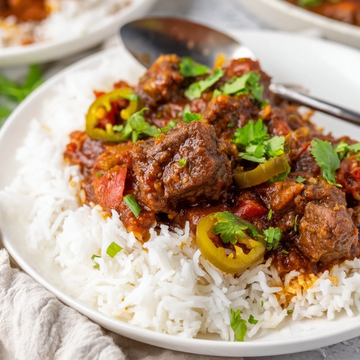 Tender beef cubes simmered in a rich, aromatic tomato sauce for a spicy beef curry over fluffy rice.