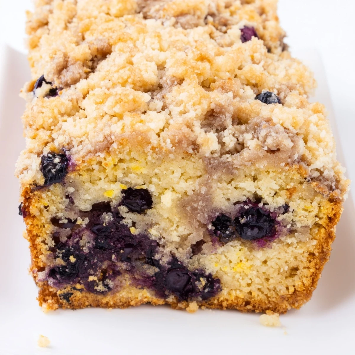 A close-up of a golden-crusted Lemon Blueberry Bread with crumbly streusel, ready to be enjoyed with coffee.
