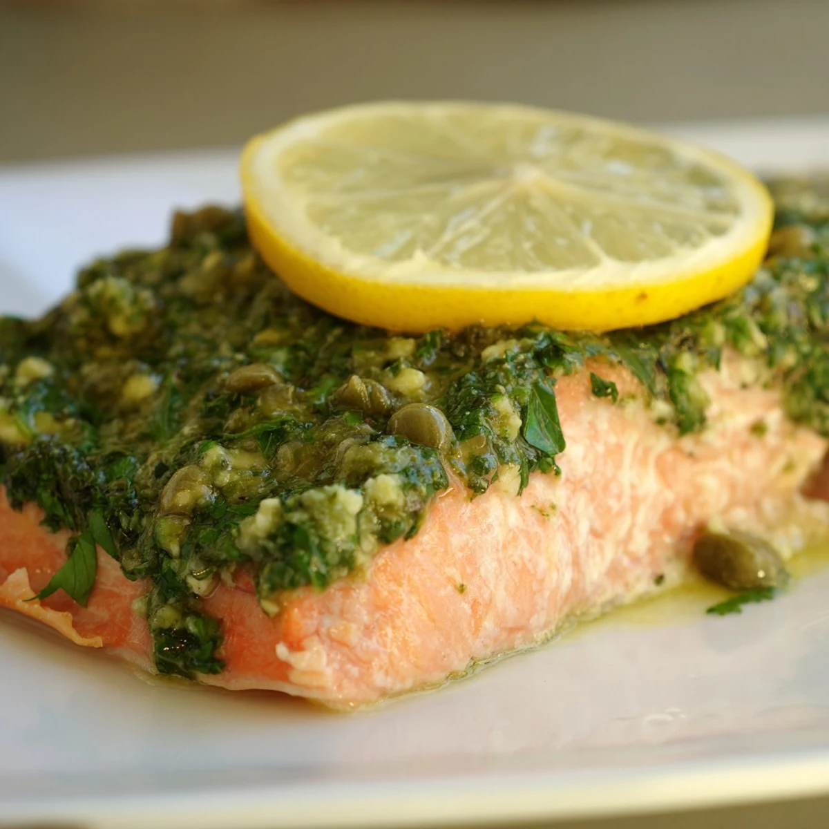 Tender baked salmon with zesty salsa verde, served on a rustic white plate for a healthy Mediterranean dinner.