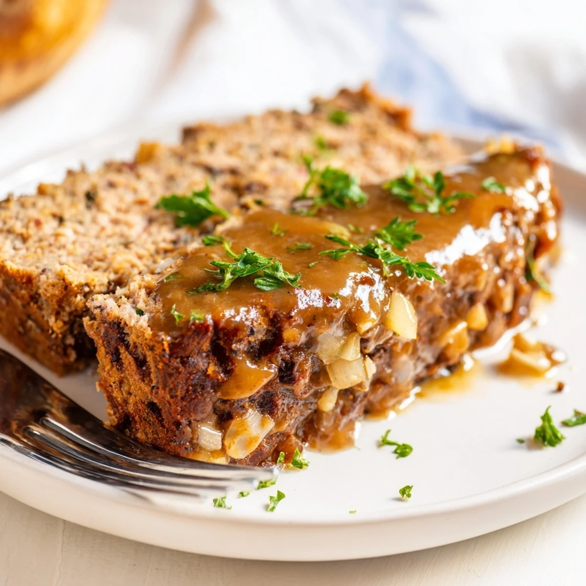 Moist Turkey Loaf with Gravy is served warm, drizzled over a slice alongside creamy mashed potatoes and green beans.