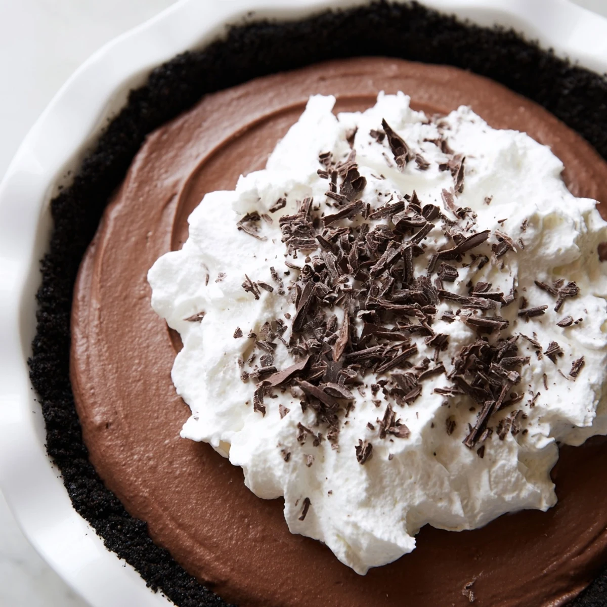 Perfect for a romantic date night, this decadent Romantic Chocolate Silk Pie is garnished with shavings and served beside fresh raspberries.
