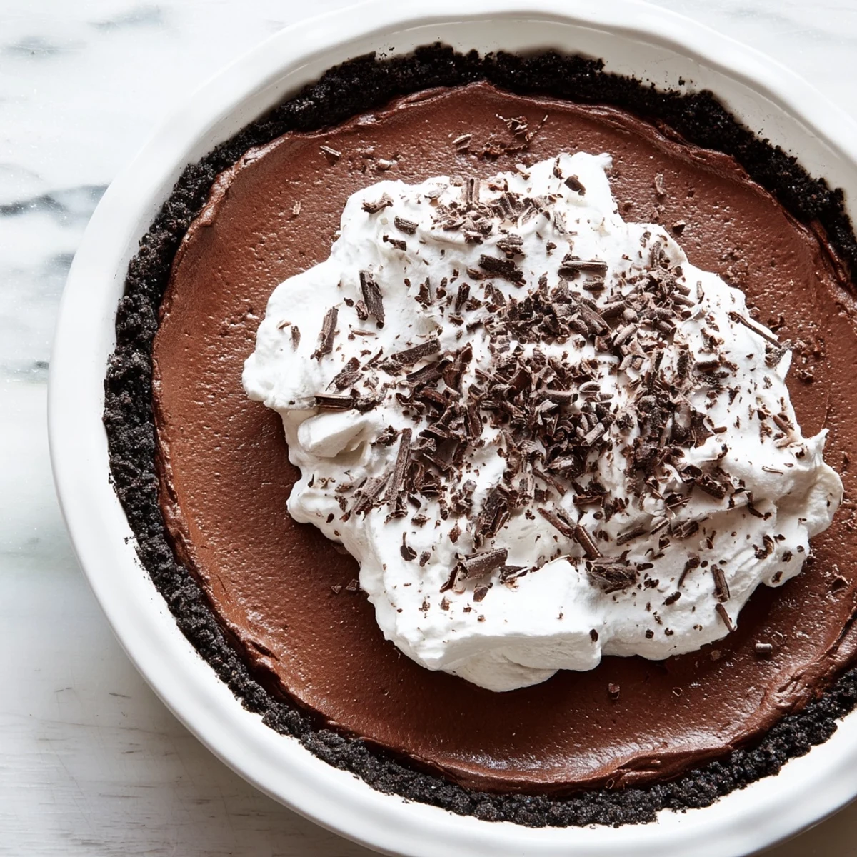 Rich, glossy chocolate silk filling peeks out of a baked cookie crust, with creamy whipped topping creating the ultimate elegant dessert presentation.