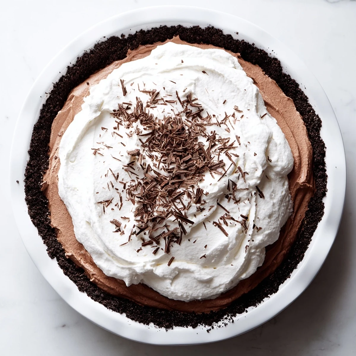 Decadent Romantic Chocolate Silk Pie with a crisp cookie crust, topped with fluffy whipped cream and chocolate curls.