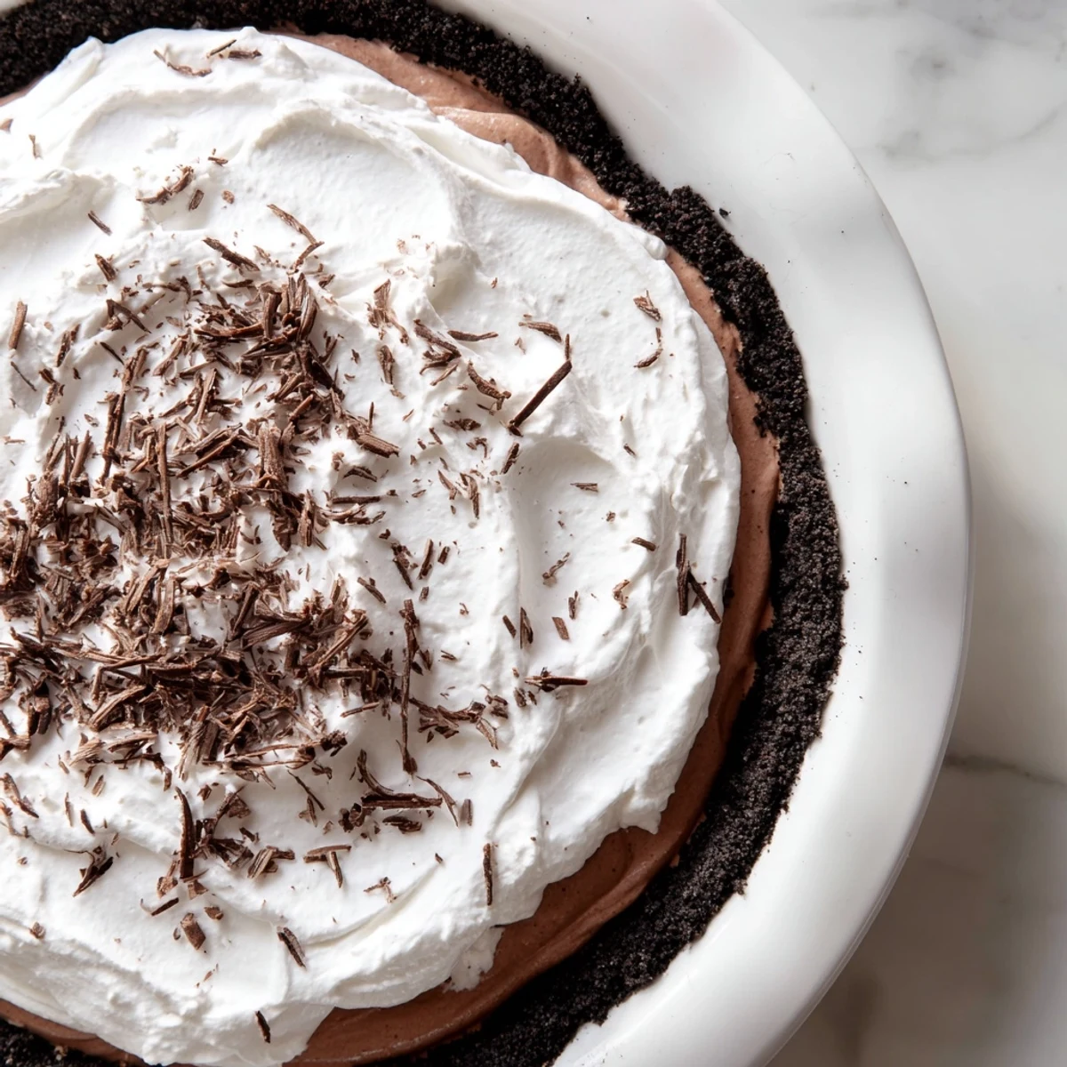 Freshly made Romantic Chocolate Silk Pie with glossy filling, whipped cream swirls, and a crunchy chocolate cookie crust.