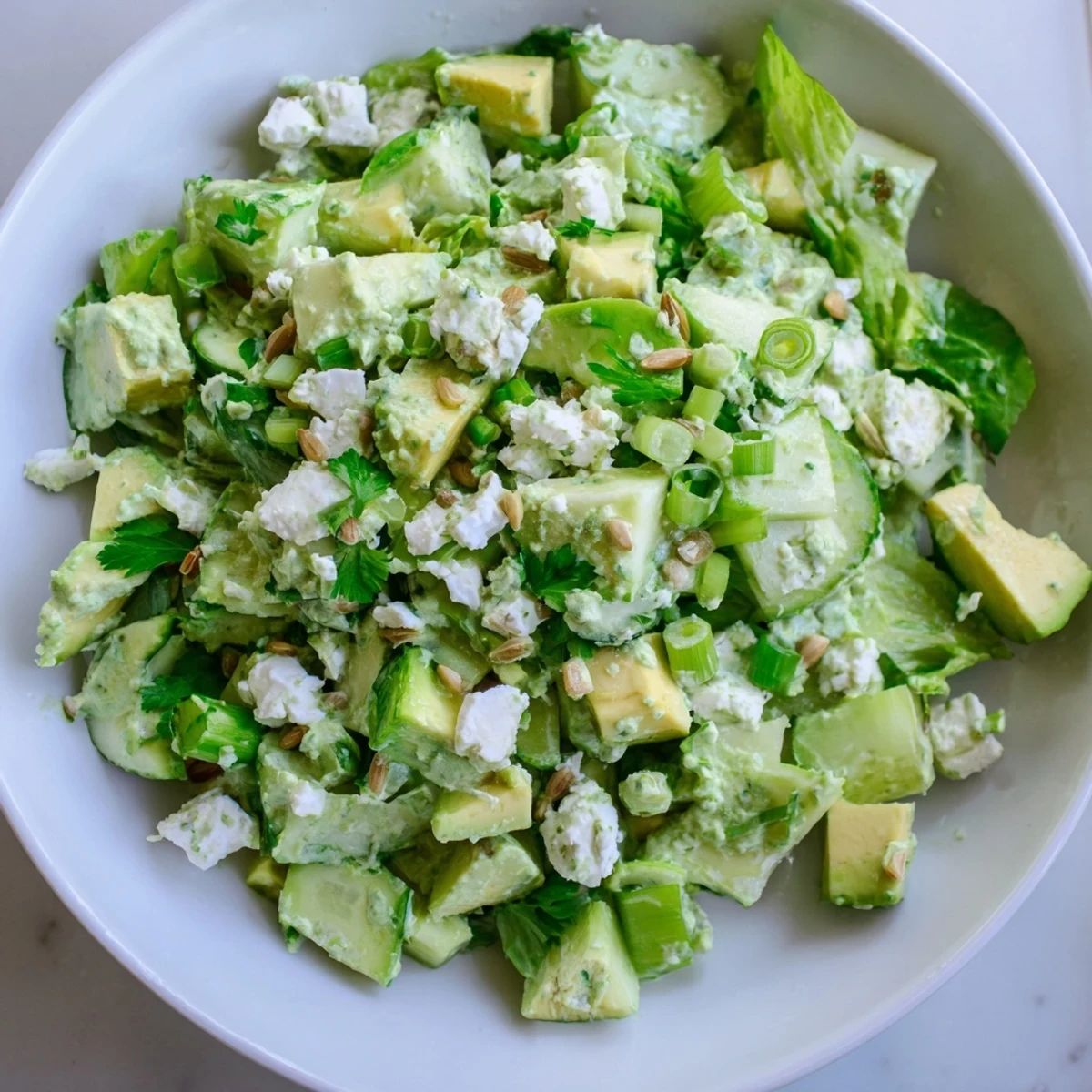 A close-up of Green Goddess Salad with crisp cucumber, ripe avocado, and tangy dressing for summer lunches.