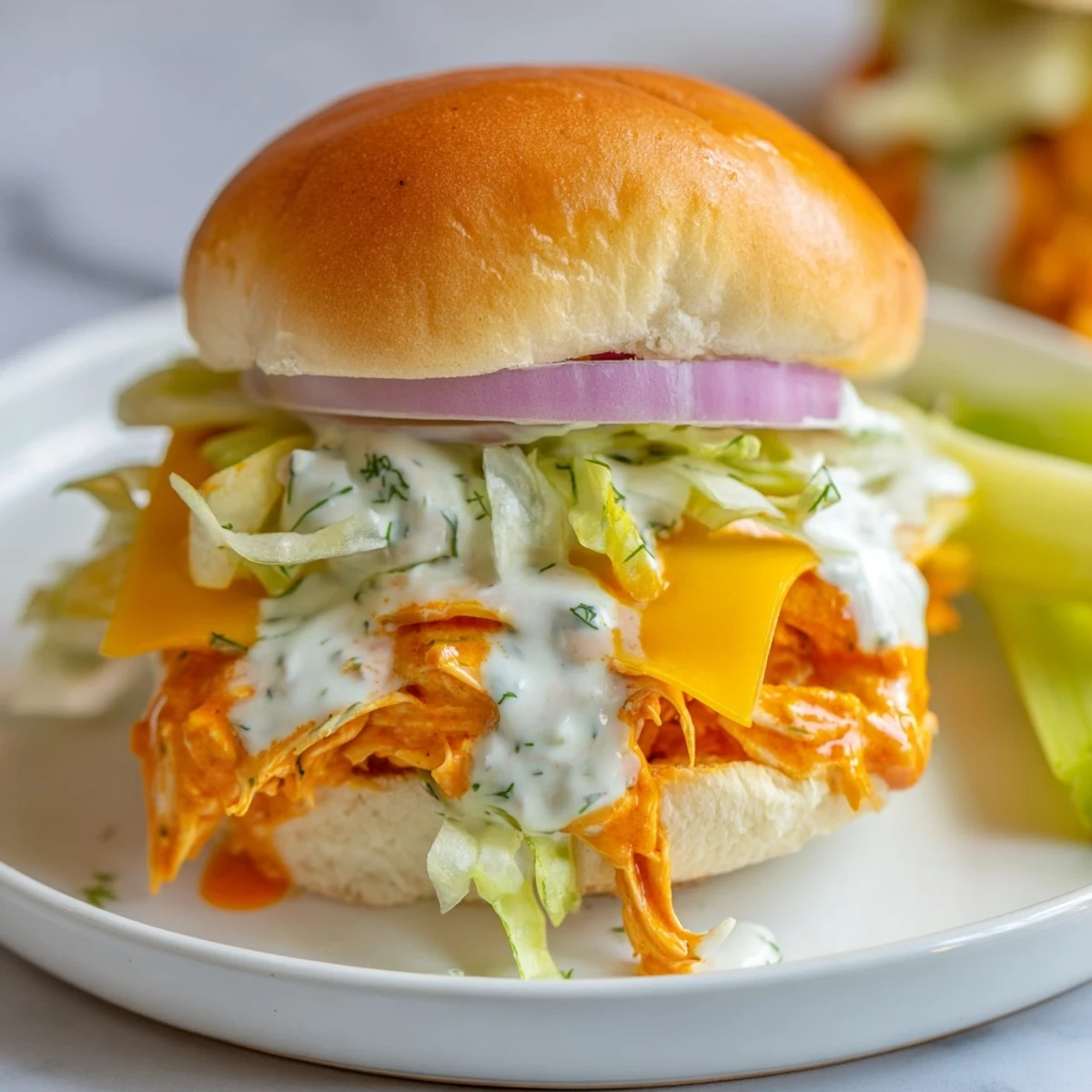 Golden Buffalo chicken sliders with ranch dressing, crisp lettuce, red onion, and celery on soft buns.
