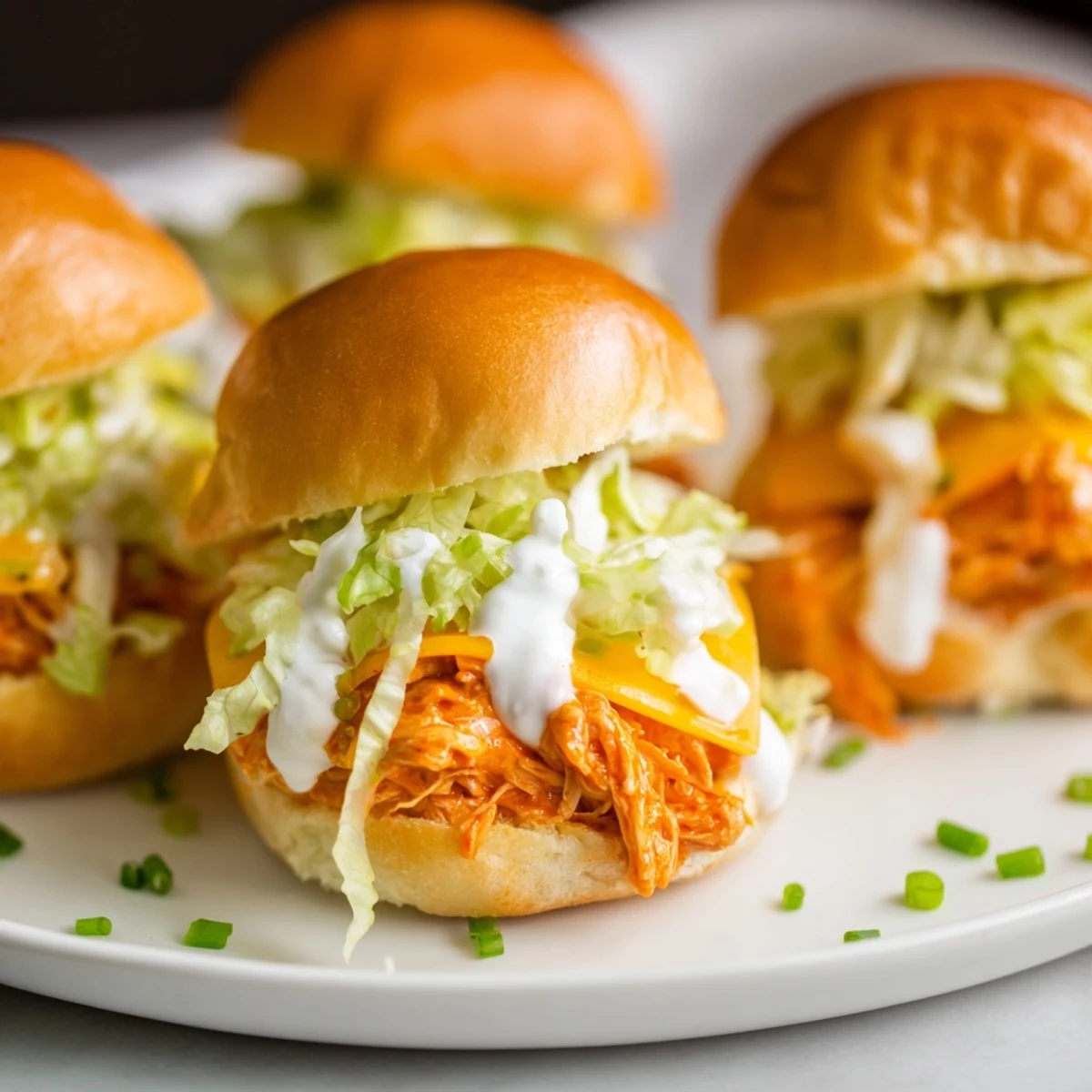 Spicy shredded buffalo chicken sliders topped with melted cheddar, fresh celery, and a drizzle of creamy ranch.
