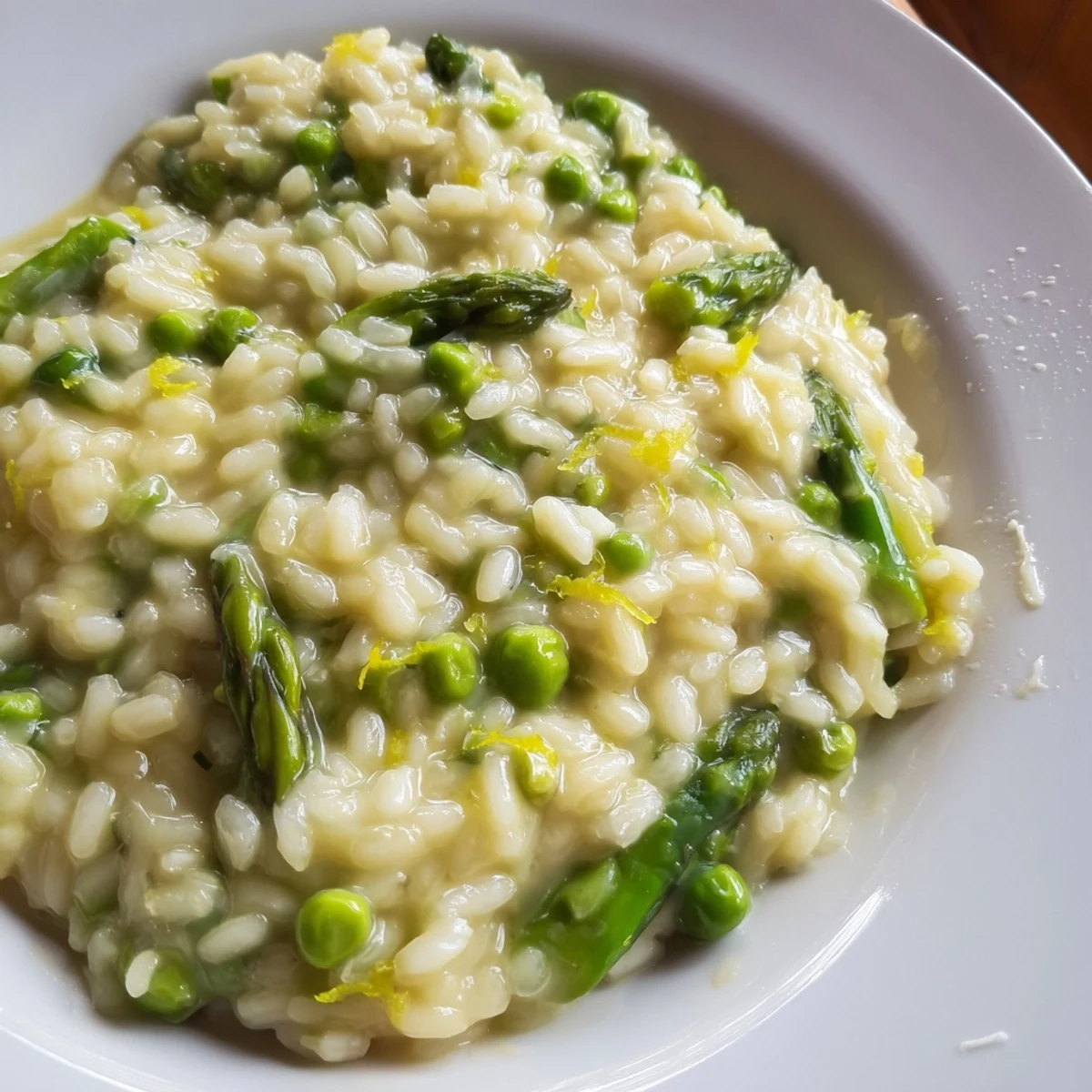 Creamy Asparagus and Pea Risotto with Parmesan served warm in a white bowl, garnished with fresh herbs.