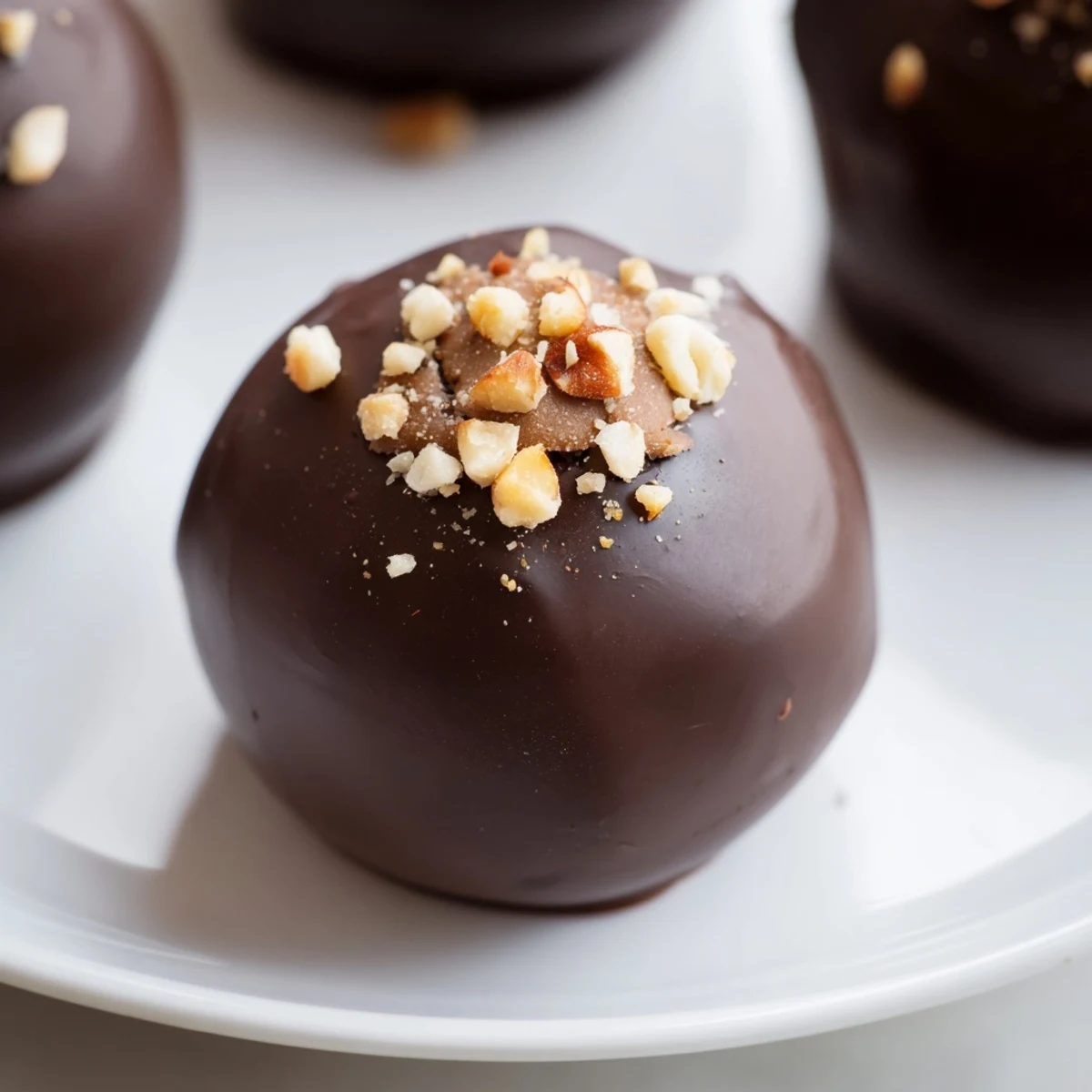 A close-up of Irish Cream Truffles with Dark Chocolate dusted in cocoa powder and topped with chopped hazelnuts.