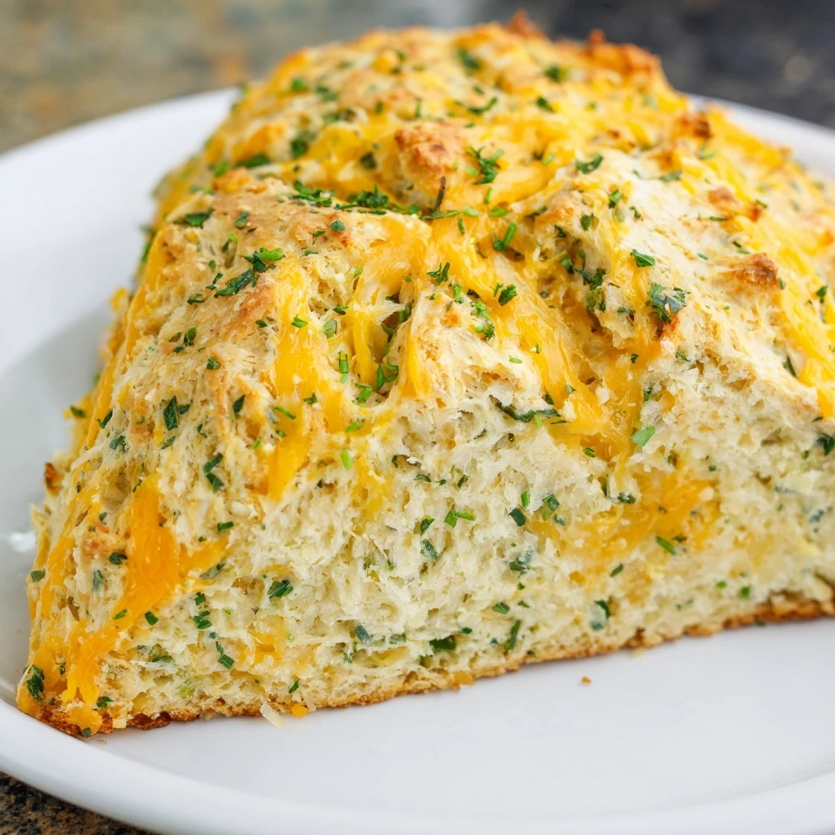 Slices of Savory Herbed Cheddar Irish Soda Bread on a wooden board, showing a moist, herbed interior crumb.
