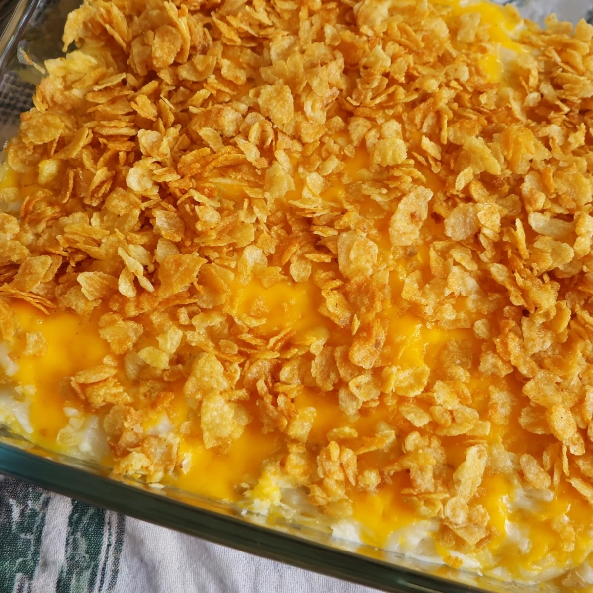 A close-up of Funeral Potatoes with Hashbrowns showing creamy cheddar sauce and crunchy melted butter crumbs.