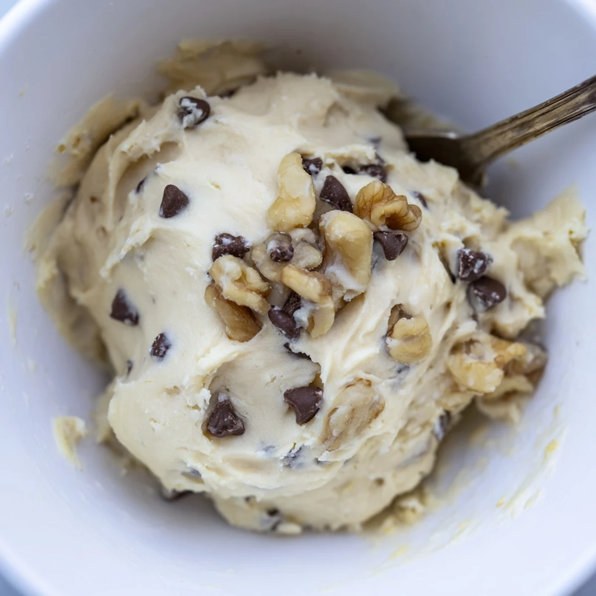 In a rustic kitchen setting, Guilt Free Greek Yogurt Cookie Dough is garnished with chopped walnuts, offering a healthy dessert option.