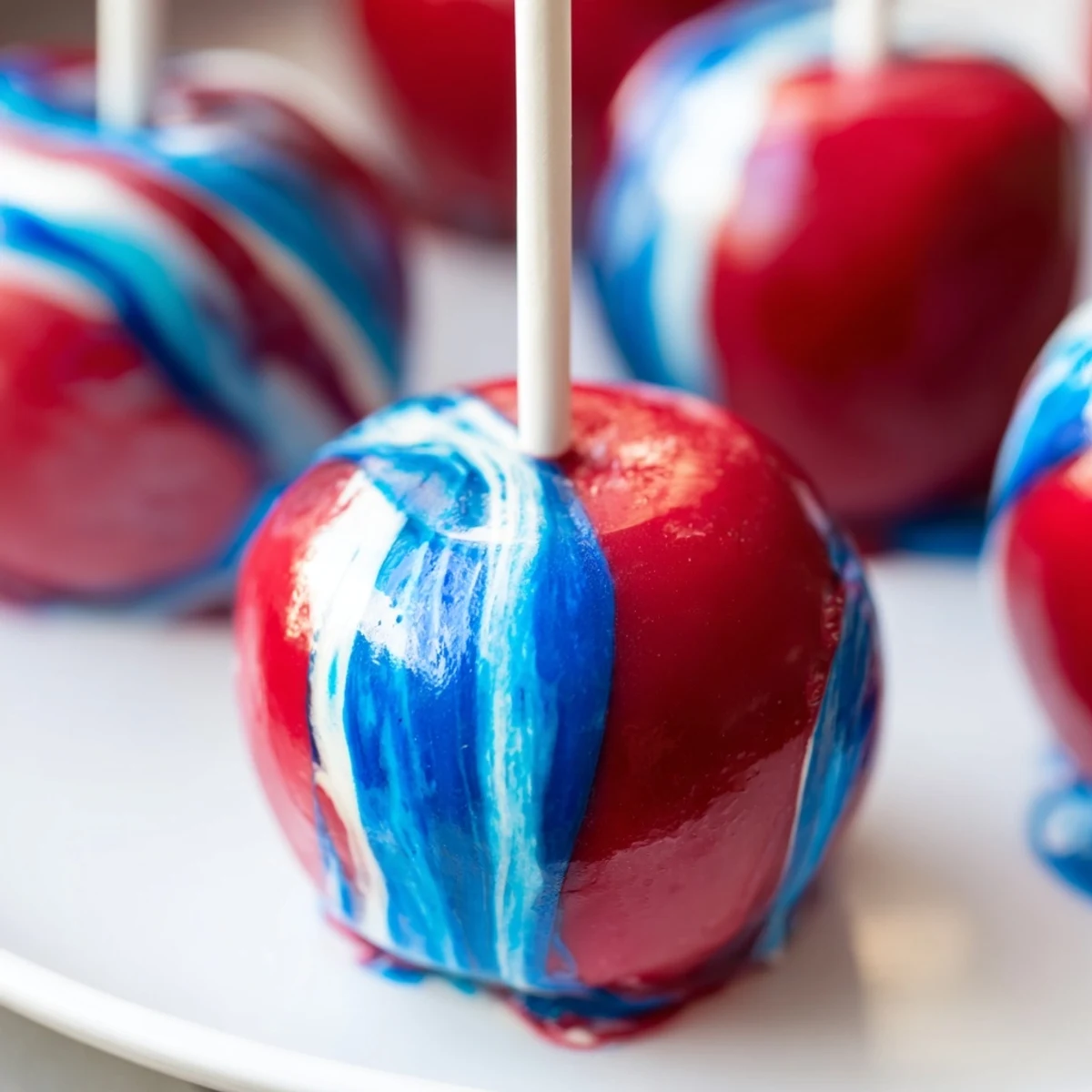 Vibrant red, blue, and white swirls coat crisp apples in this Marbled Effect Candy Apples dessert, arranged for a party.