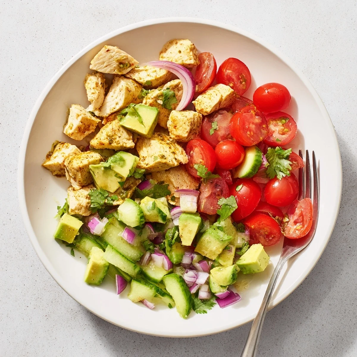 A freshly tossed avocado chicken salad served over greens with lime dressing for a light lunch.