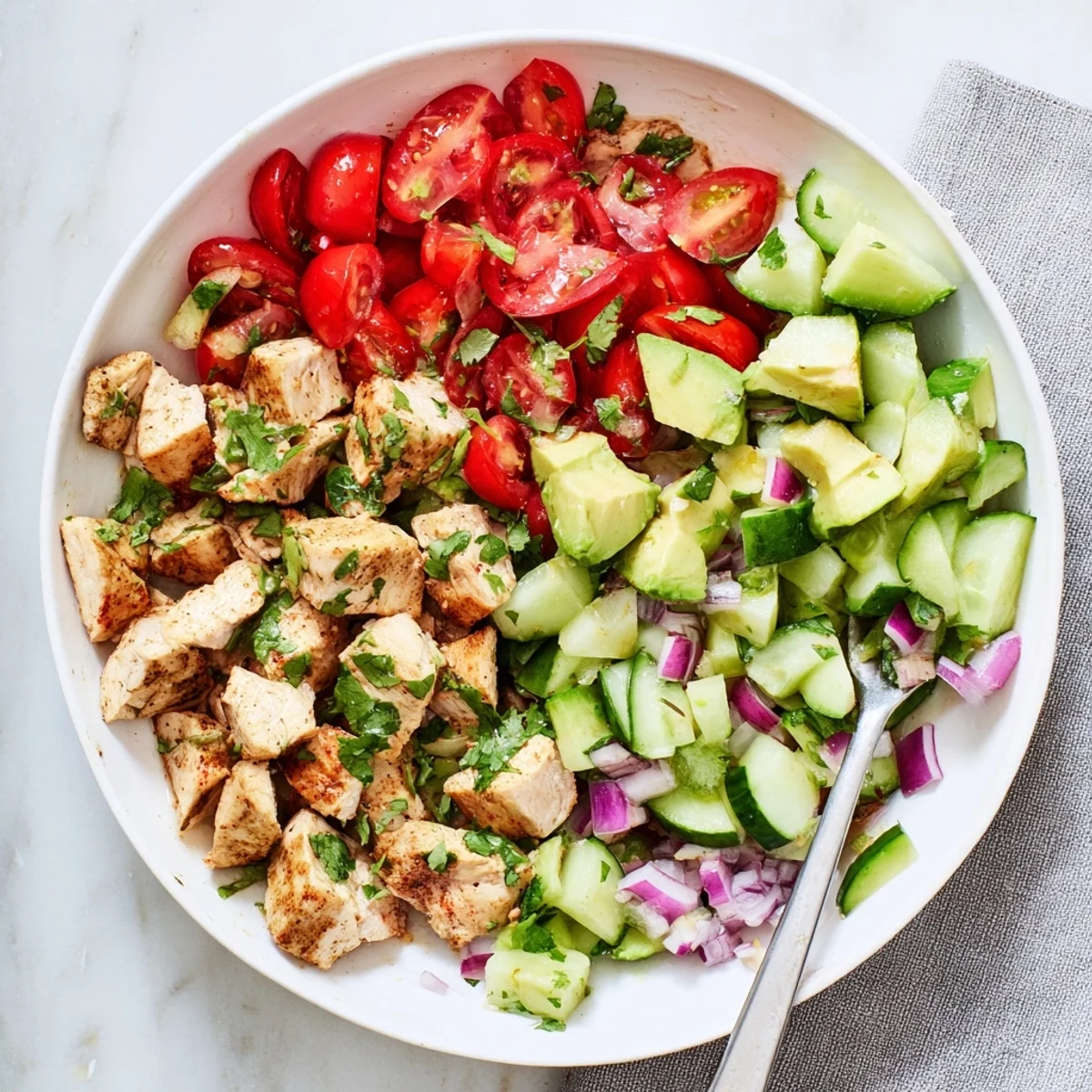 Sliced grilled chicken breast mixed with ripe avocado and crisp vegetables in a vibrant salad bowl.