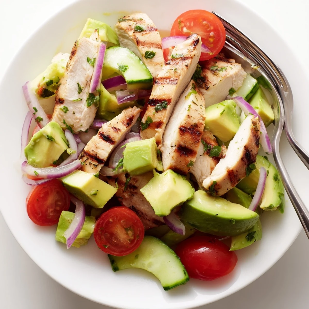 Freshly grilled diced chicken breast sits atop mixed greens with diced avocado, cherry tomatoes, and cucumber in this Avocado Chicken Salad. 