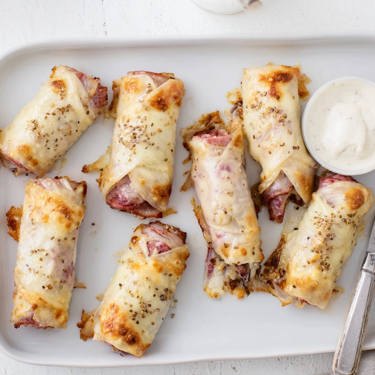 Two Keto Crispy Reuben Roll Ups sliced open to reveal layers of corned beef, sauerkraut, and melted Swiss cheese inside.
