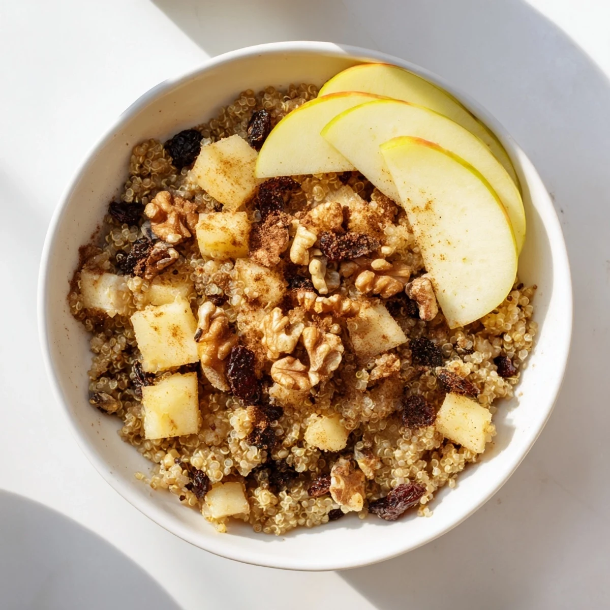 Steaming bowl of Healthy Quinoa Apple Breakfast topped with walnuts and sweet honey drizzle.