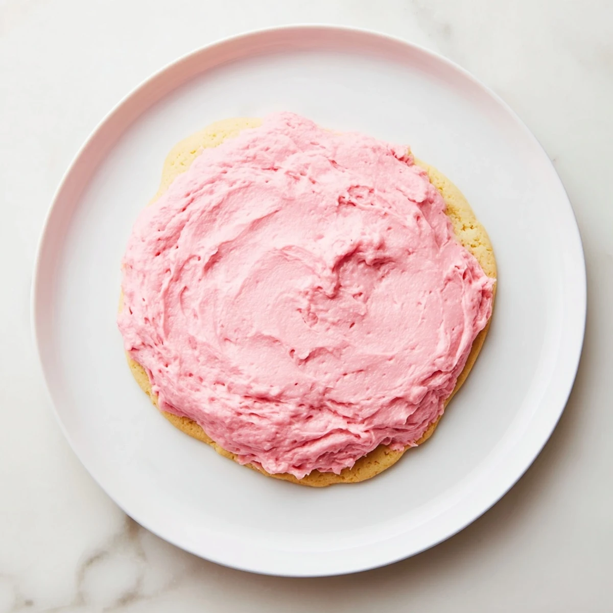 Homemade Crumbl Pink Sugar Cookies plated with a glass of milk, showcasing soft, buttery texture and pink frosting.