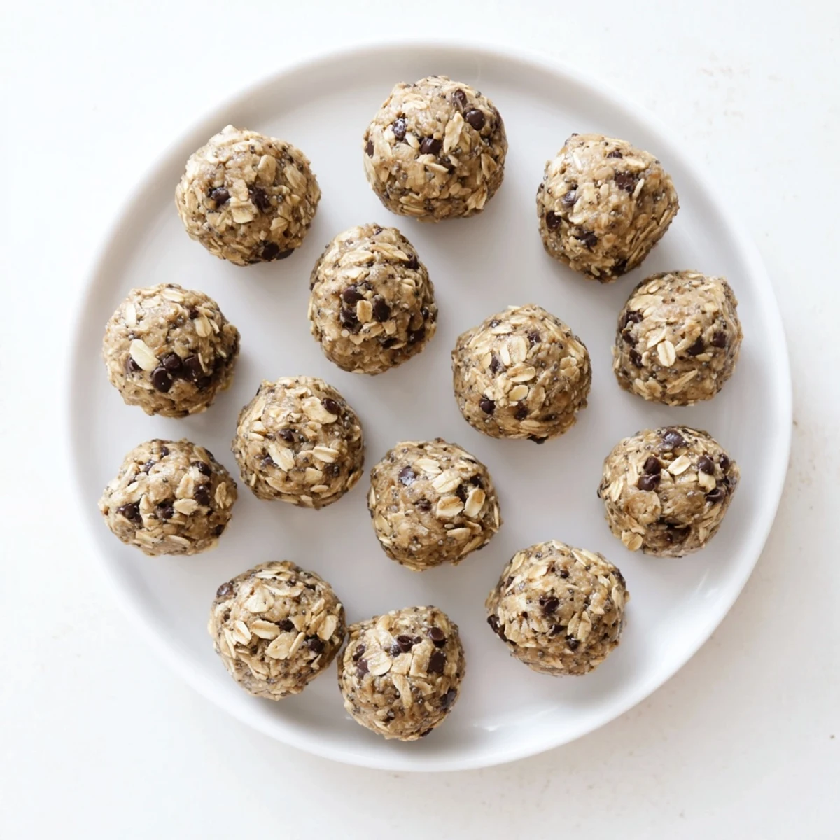 A hand holding a Mint Chocolate Chip Protein Ball, showing bite marks and gooey chocolate chips inside.