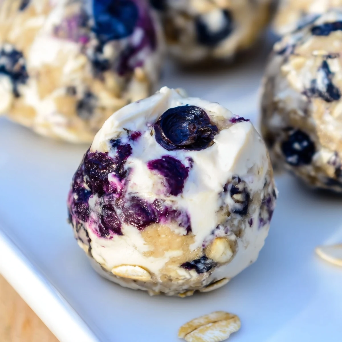Twelve round Blueberry Cheesecake Protein Bites stacked on a cooling rack, featuring a creamy filling and rolled oats texture, ideal for post-workout energy.
