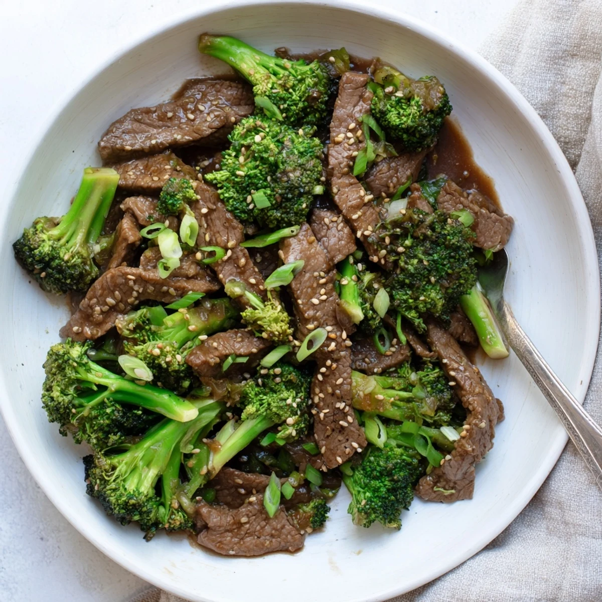 Homemade Better Than Takeout Beef With Broccoli plated with sautéed aromatics and a glossy garlicky sauce for a weeknight dinner.