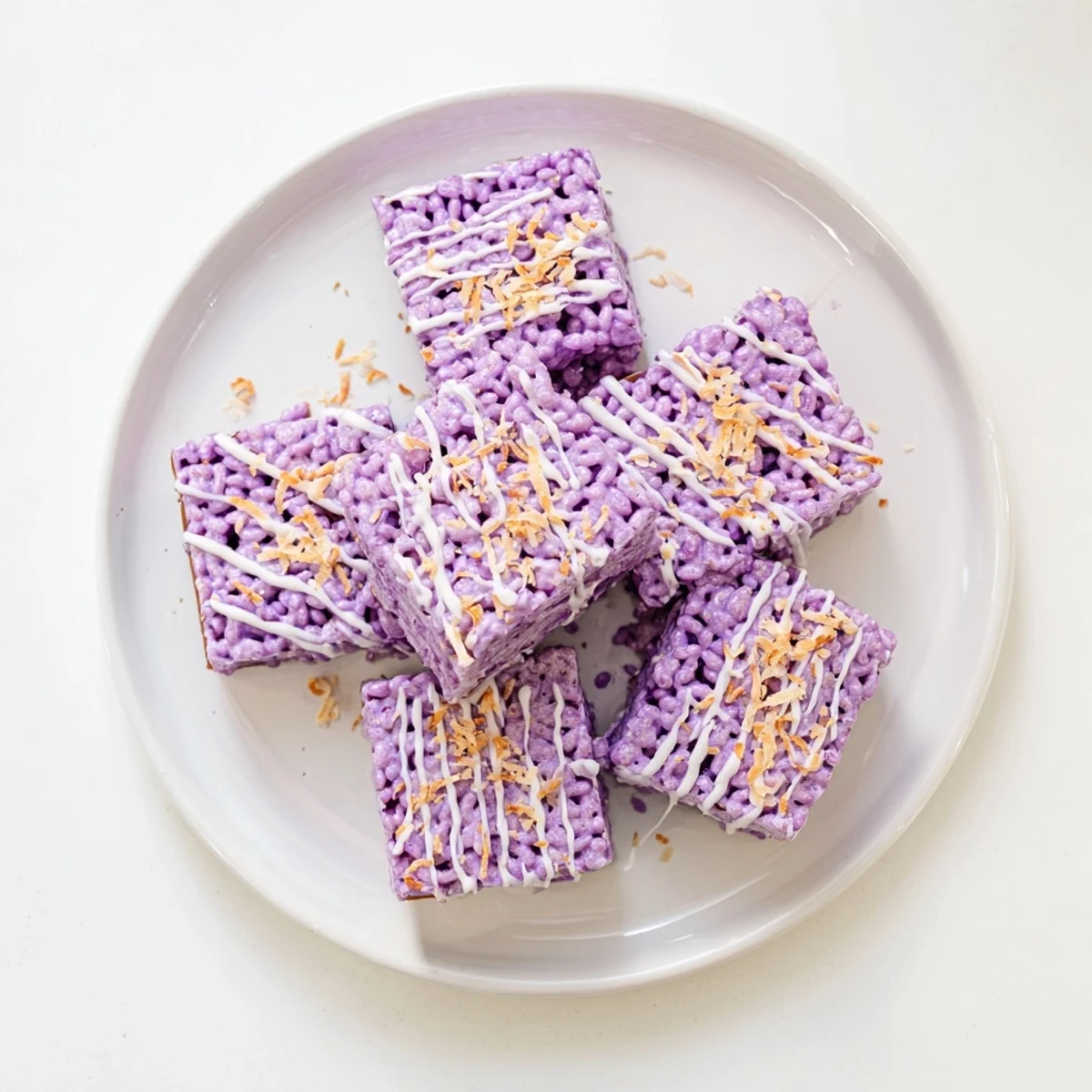 Vibrant purple ube rice krispie treats drizzled with white chocolate and toasted coconut flakes