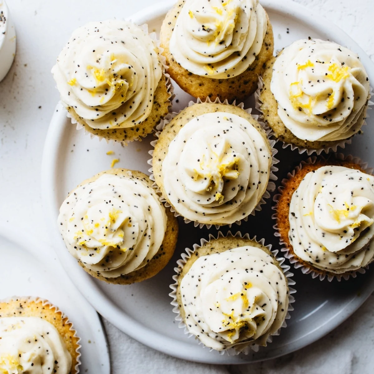 Freshly baked lemon poppy seed cupcakes garnished with lemon zest and crunchy poppy seed sprinkles