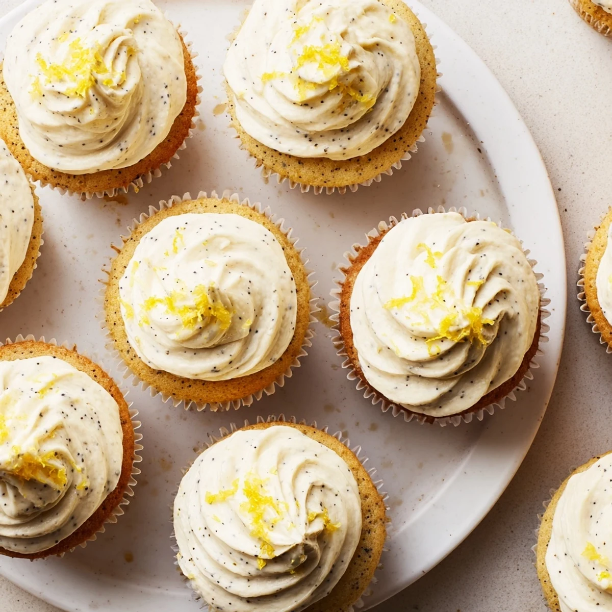 Moist lemon poppy seed cupcakes with speckled texture and tangy cream cheese frosting piped high