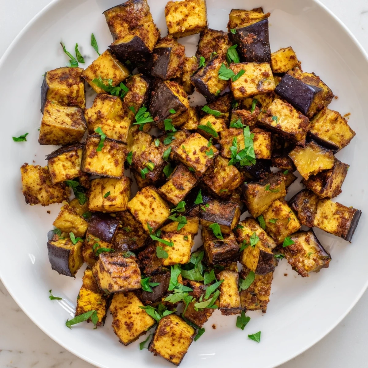 Crispy tender low calorie air fryer eggplant garnished with fresh parsley and drizzled with bright lemon juice