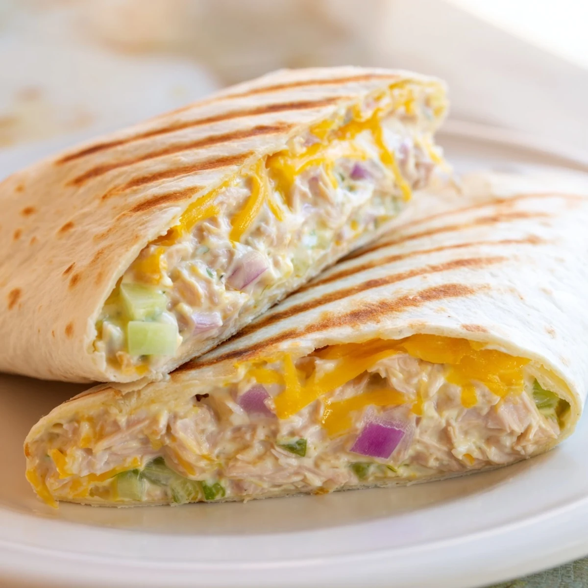 Golden grilled tuna melt wrap with melted cheddar oozing from warm flour tortilla