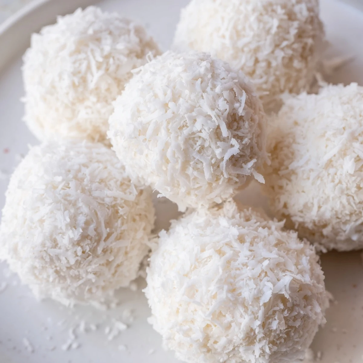No bake Easter bunny coconut tails dusted in white powdered sugar on a rustic wooden board
