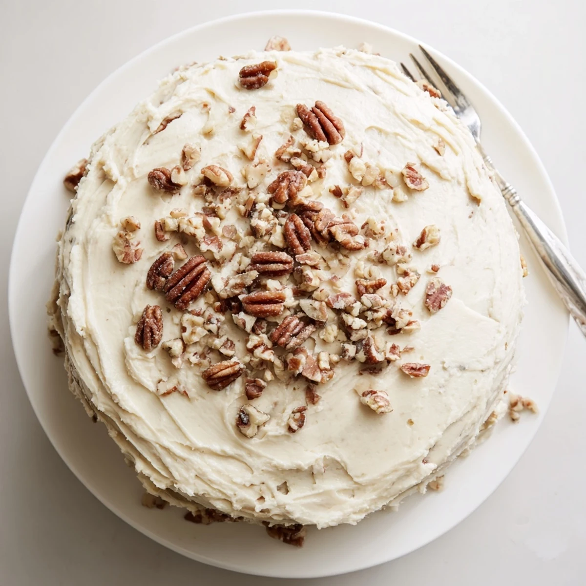 Golden butter pecan cake slice topped with creamy frosting and toasted pecans