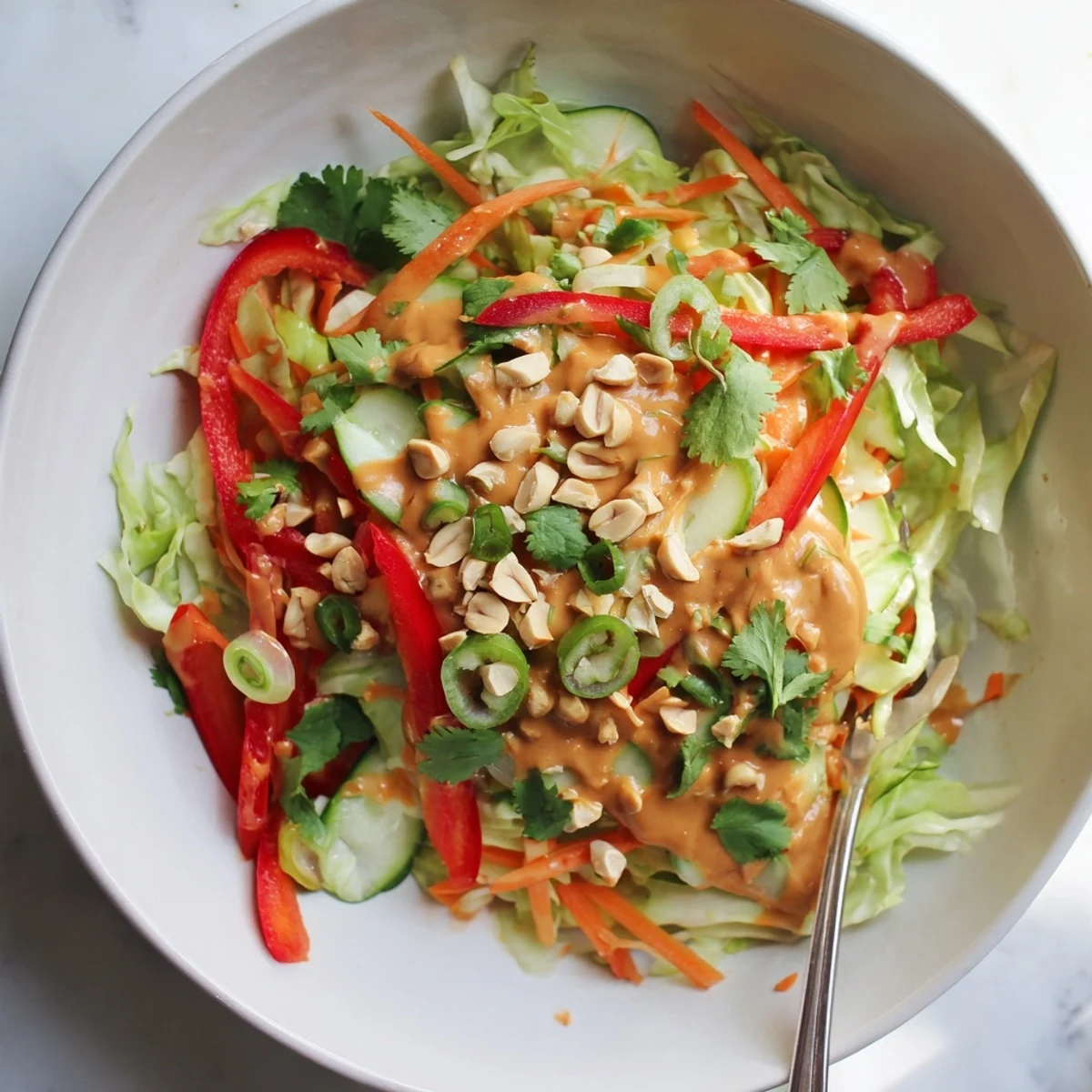 Fresh Thai salad peanut sauce drizzled over crisp cabbage, carrots, peppers, cucumber, and cilantro