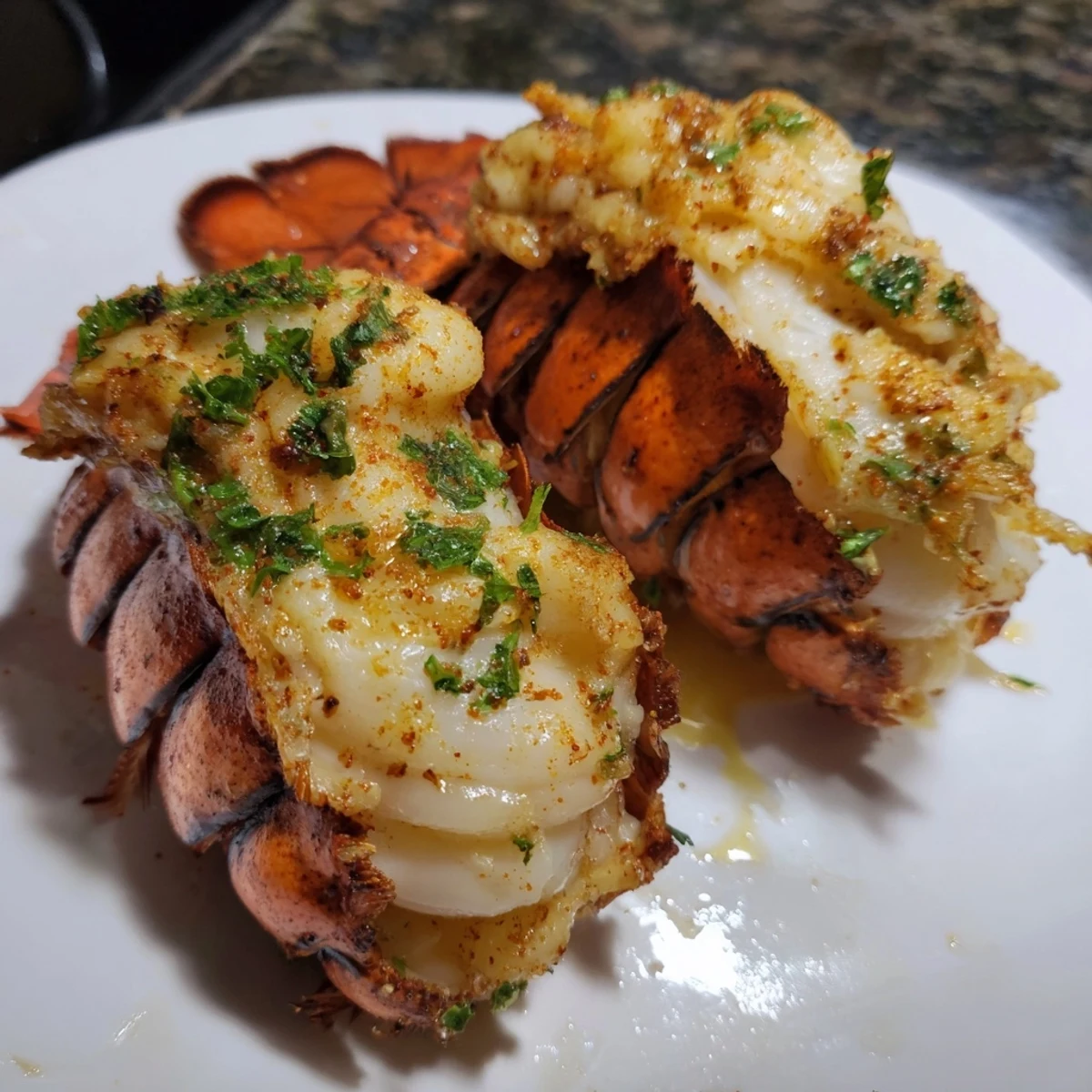 Whole roasted lobster tails swimming in rich melted garlic butter with lemon wedges