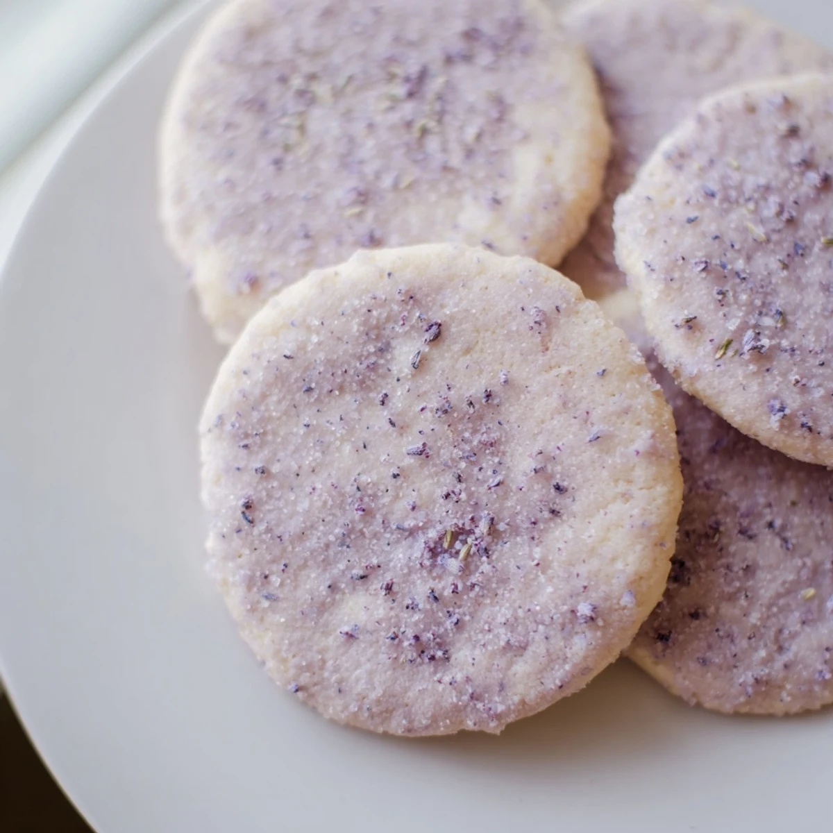 Buttery lilac sugar cookies with lightly golden edges served alongside steaming tea cup