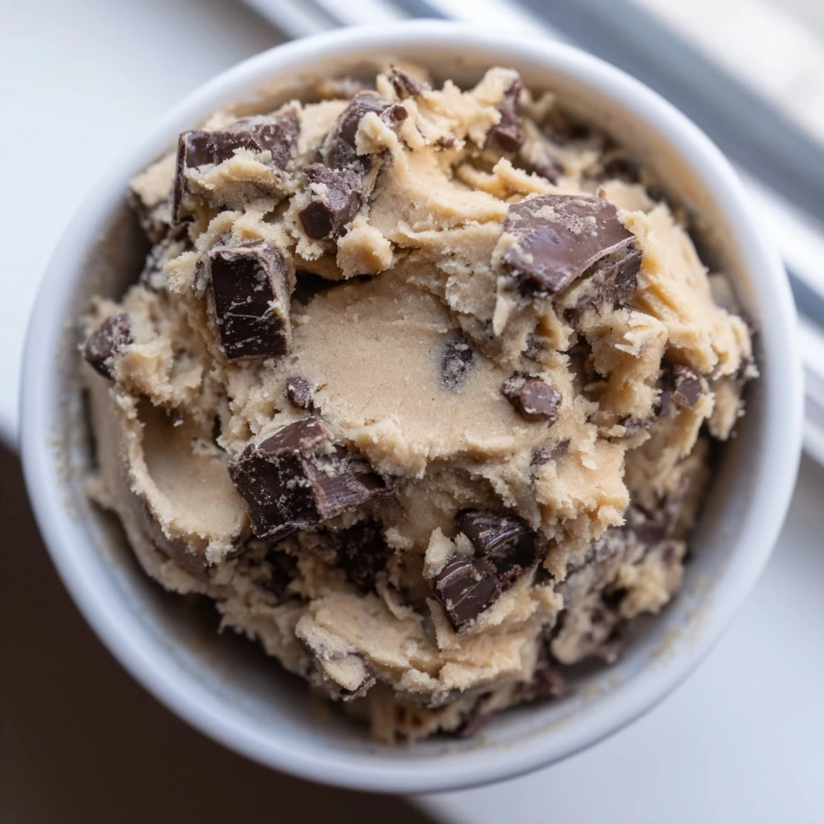 Creamy chocolate chip cookie dough scooped into balls with plenty of chocolate chips