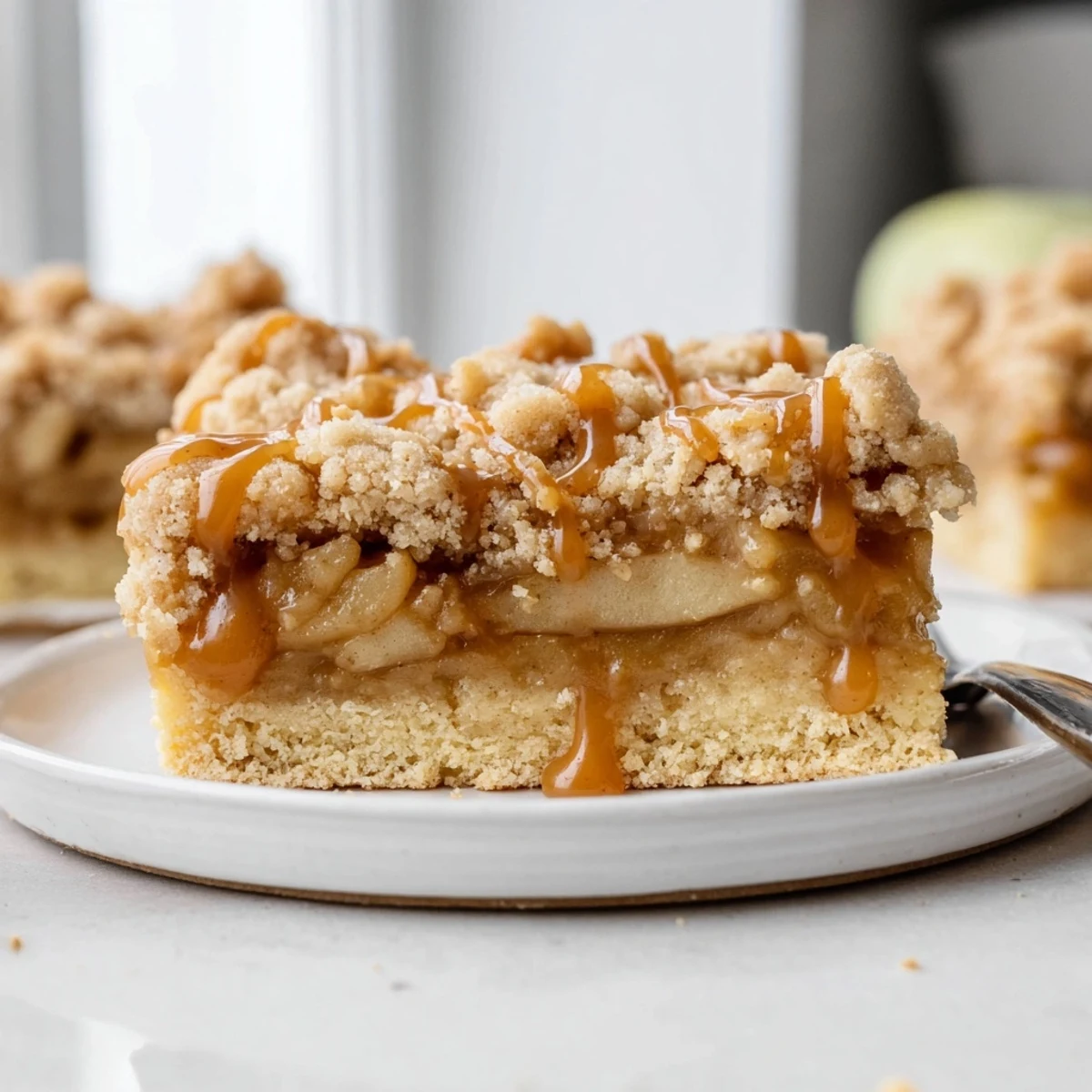Warm caramel apple crumb bars cut into squares showing tender cinnamon apple layers inside