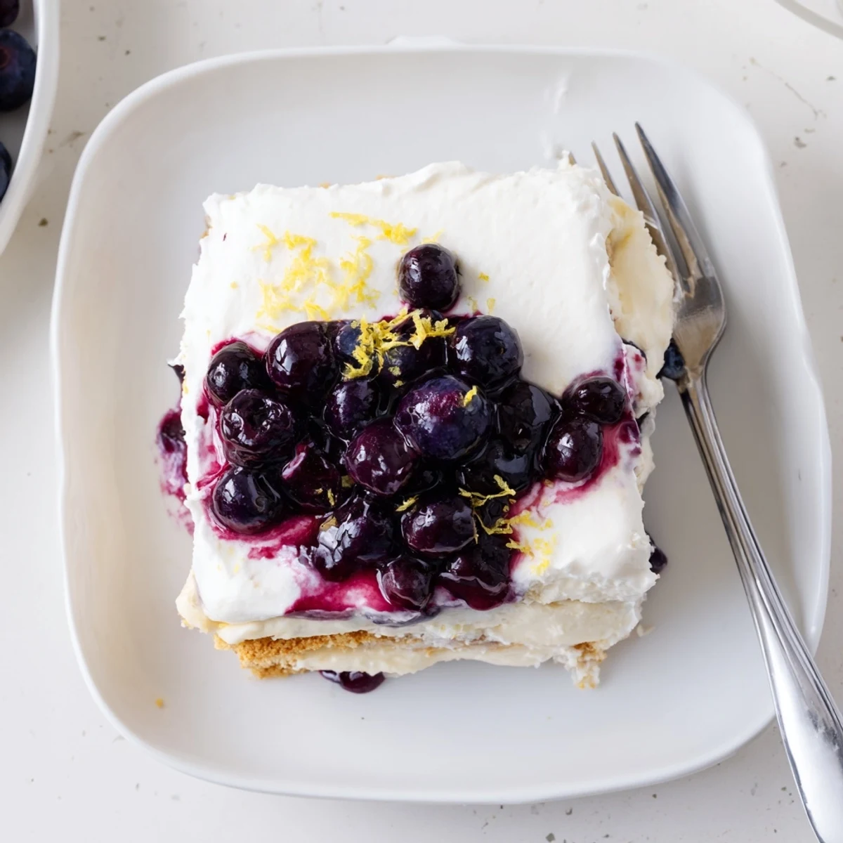 Sliced lemon blueberry lasagna showing creamy layers dotted with purple blueberry sauce