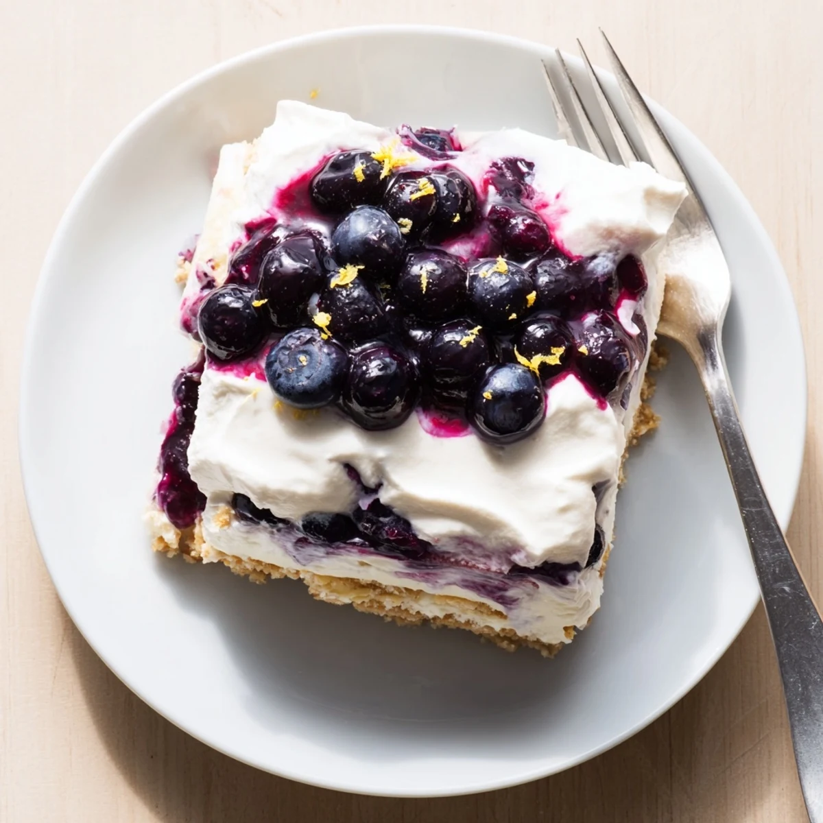 A square of lemon blueberry lasagna with golden cookie crust and bright filling