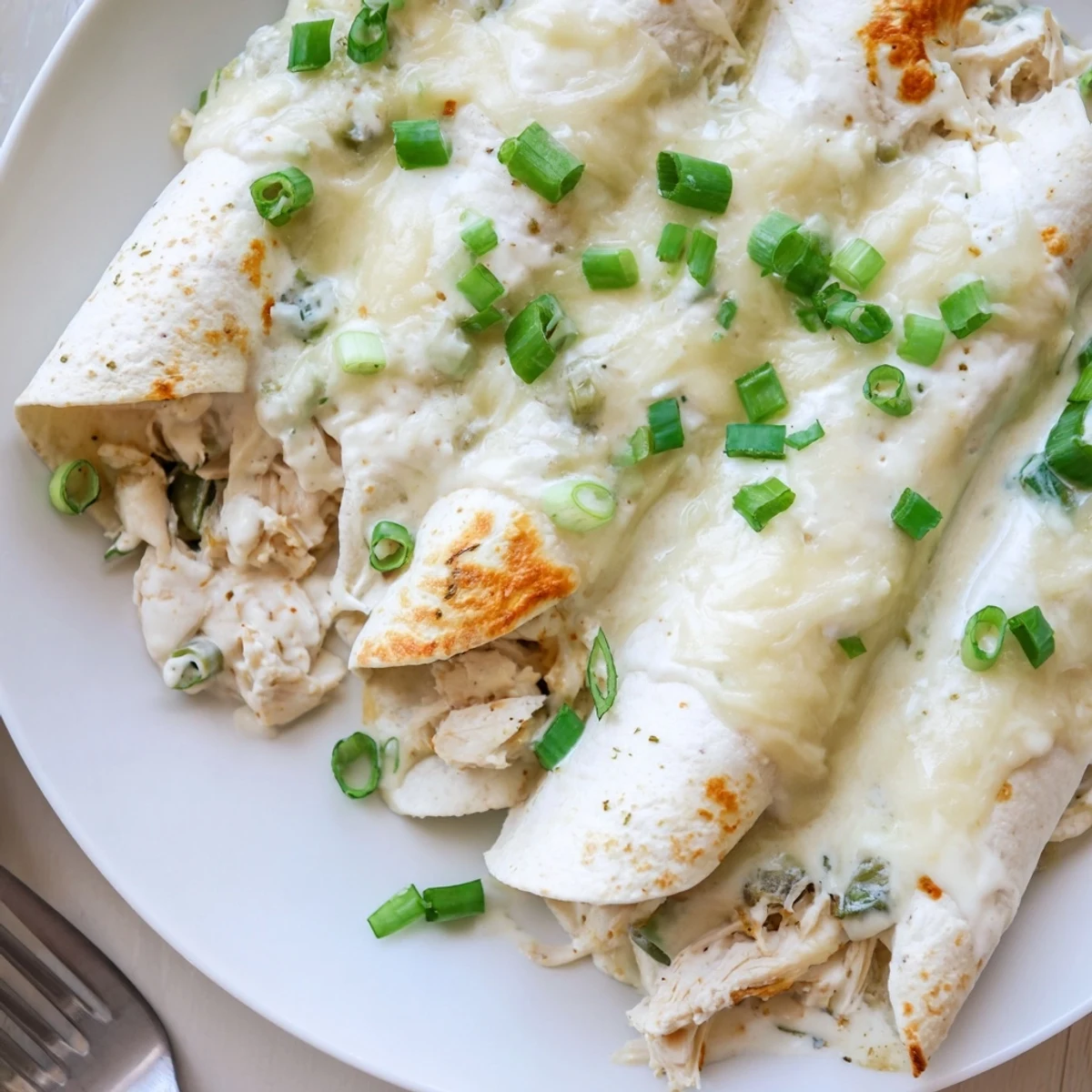 Creamy White Chicken Enchiladas bubbling golden, shredded chicken, cilantro garnish, ready to serve
