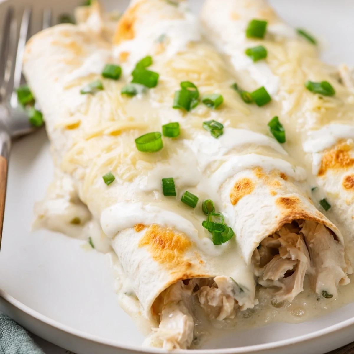 Creamy White Chicken Enchiladas sliced, steam rising, suggested with Spanish rice and salad