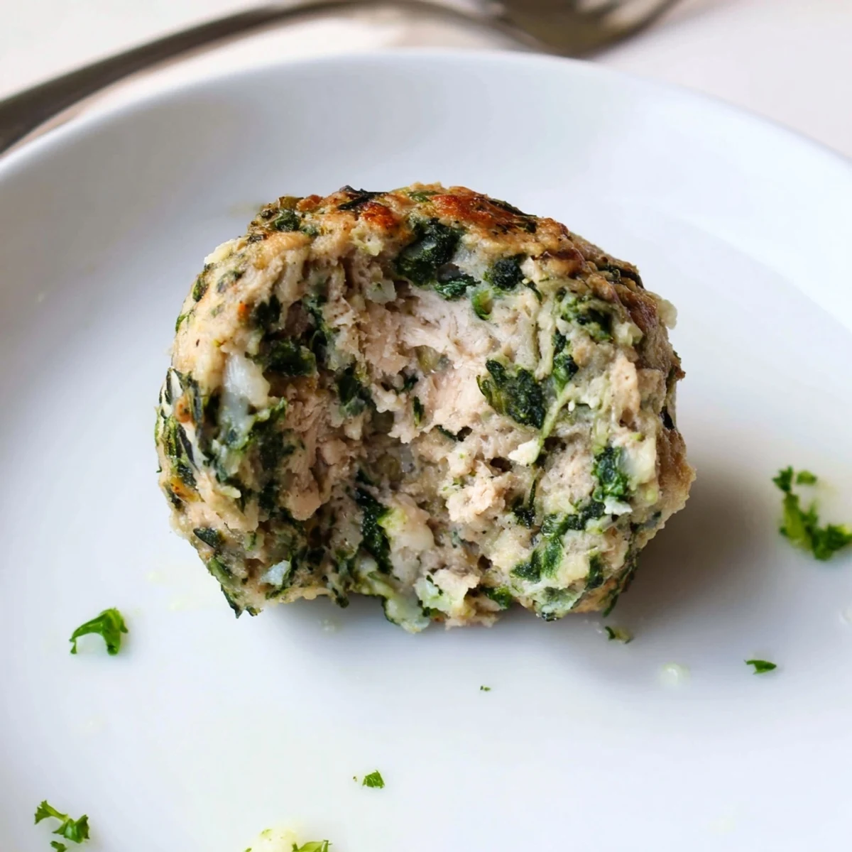 Low Carb Spinach Chicken Meatballs glistening golden, served with cauliflower rice.