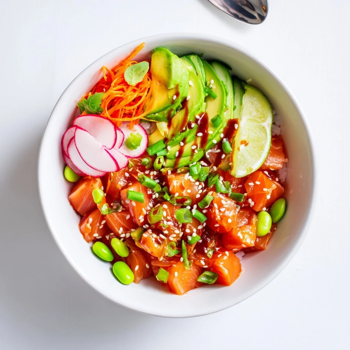 Chilled Salmon And Avocado Poke Bowl drizzled with spicy mayo, lime wedge