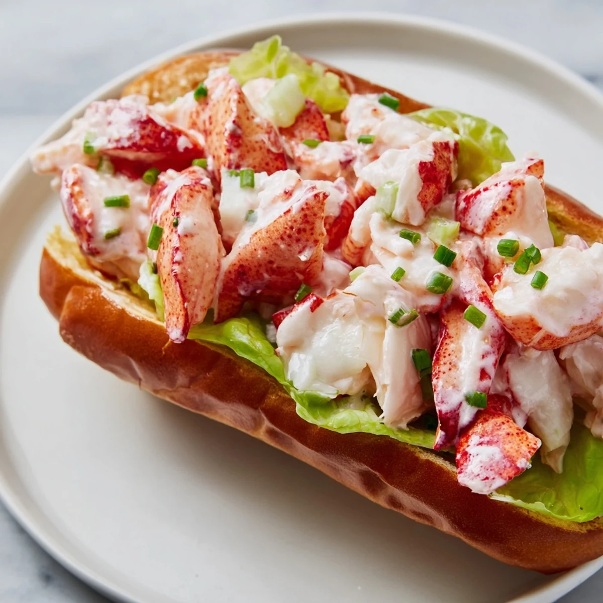 Generous portion of sweet lobster meat in a Maine style lobster rolls served on toasted New England bun