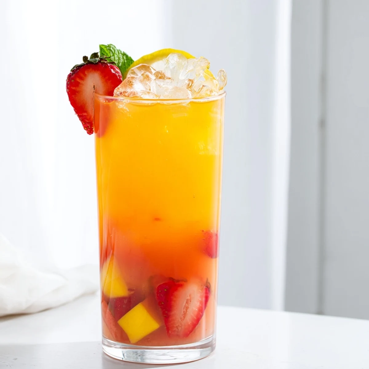 Vibrant pink mango strawberry lemonade served over ice with floating fruit slices on a sunny afternoon