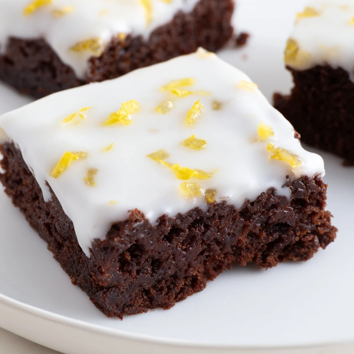 Square lemon brownies drizzled with sweet icing and sprinkled with vibrant yellow lemon zest