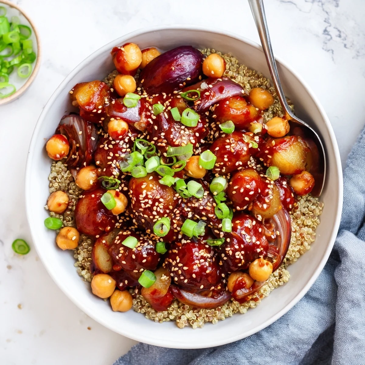 Hearty Korean-inspired grain bowl with crispy glazed potatoes chickpeas quinoa and fresh green onion toppings.